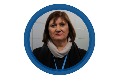 Pictured Julie Burgess dark bob hair with fringe, dark pink lipstick wearing a black and grey cowl neck jumper - and NSS blue lanyard.
